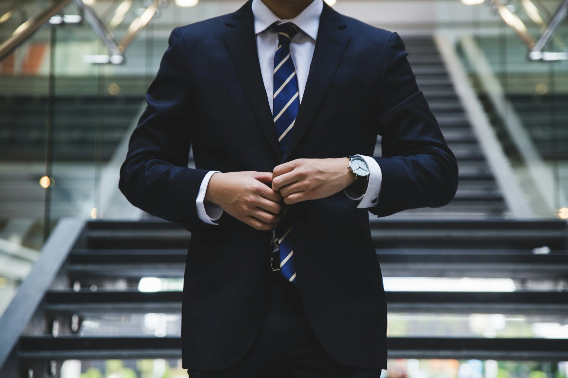 Man buttoning a navy suit jacket