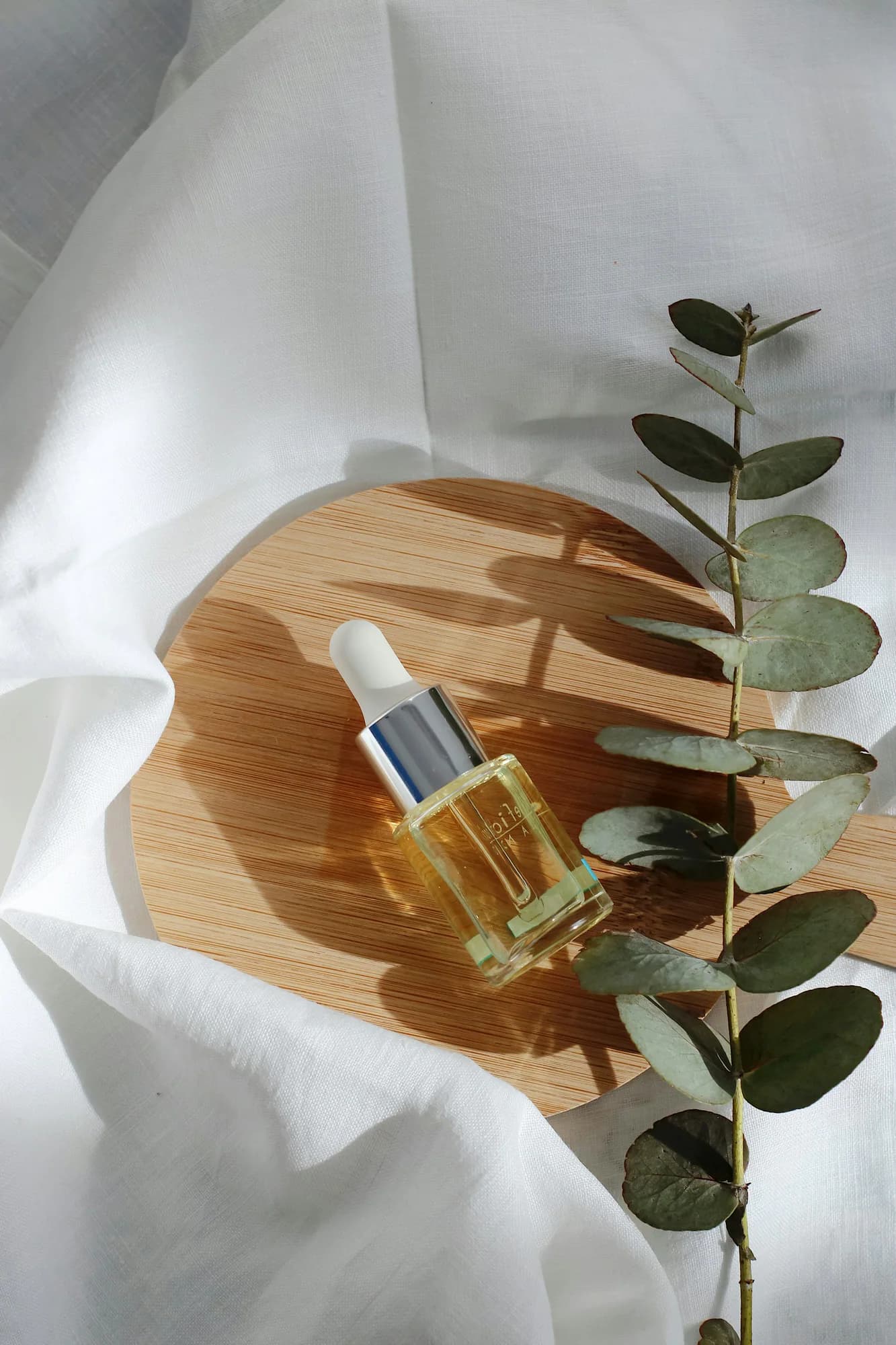 Amber dropper bottle of face oil with green leaves
